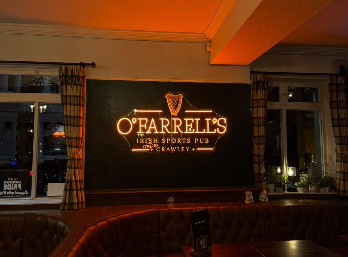 The amber neon O'Farrell's Irish Sports Pub sign glowing over dark panelling inside the pub